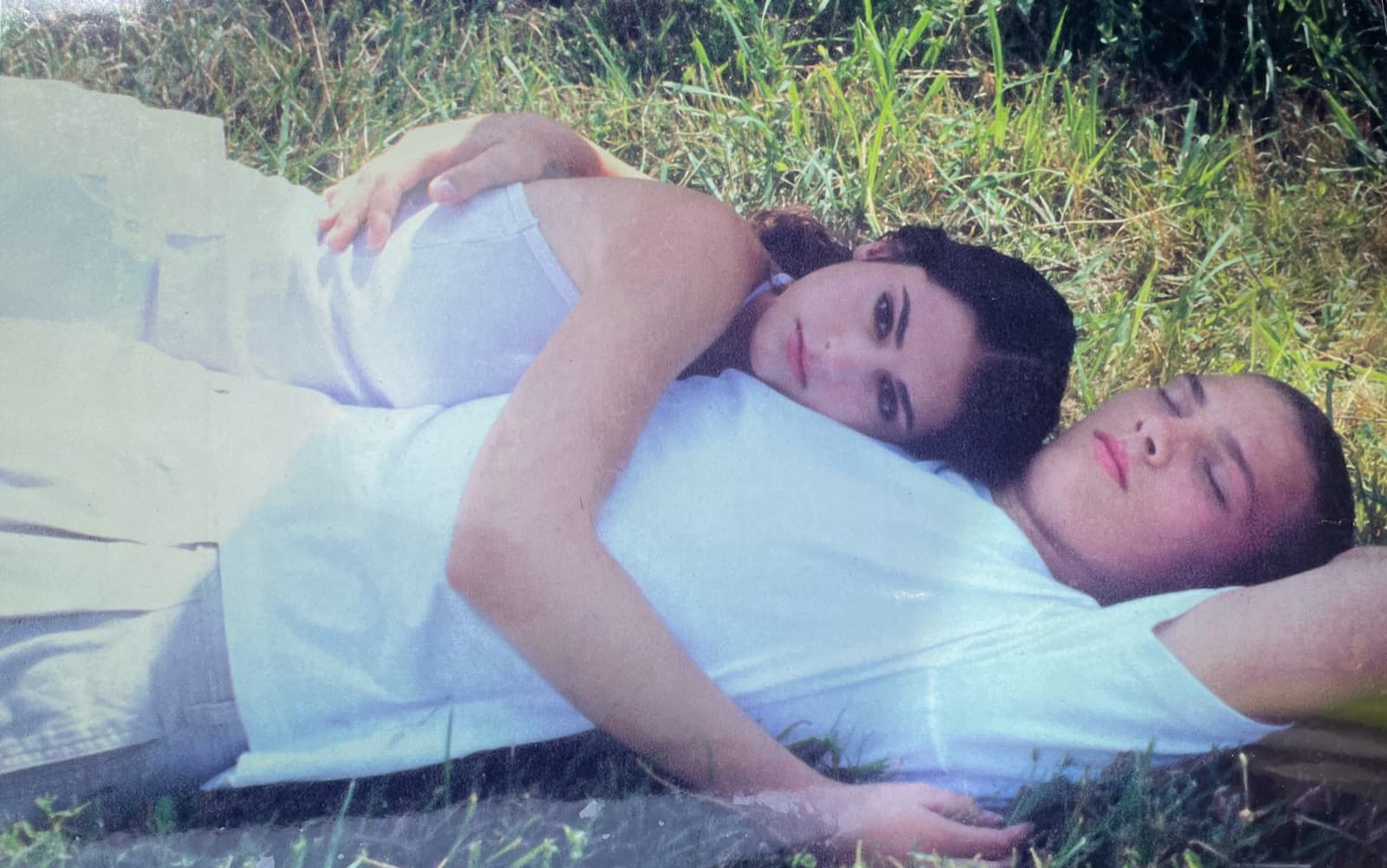 Laura and Nicholas as teenagers, lying in the grass