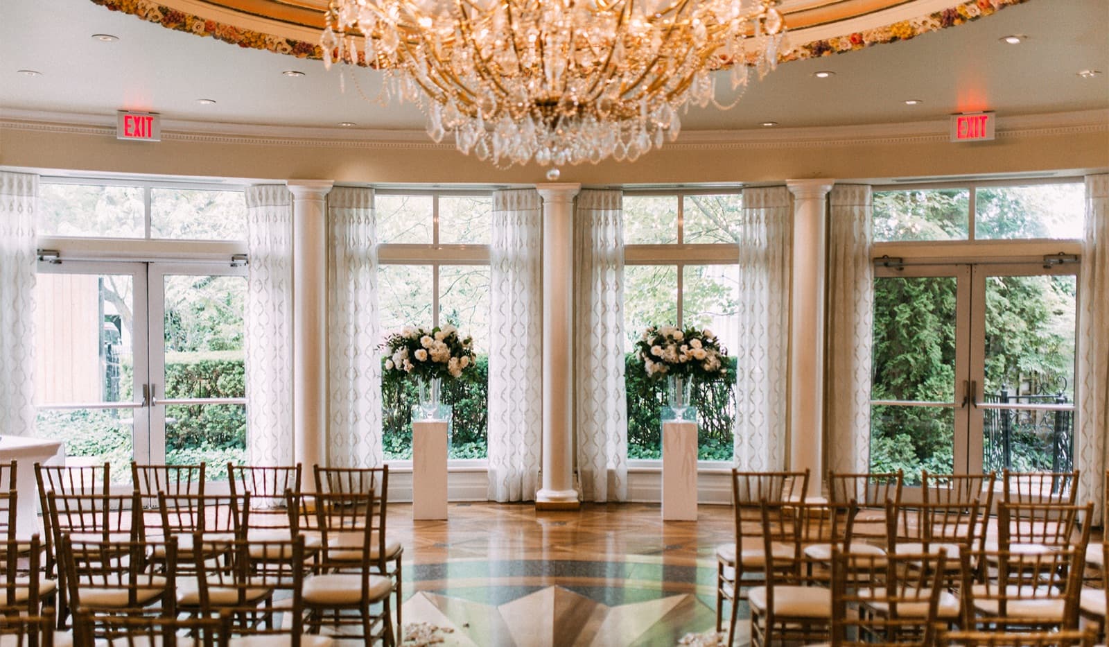 The Atrium at Queen's Landing — chandelier, columns, and garden windows